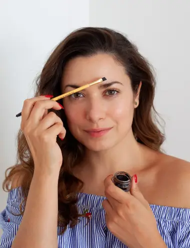 Mujer usando balsamo Brownie para pintar y fortalecer cejas y brocha de bambu ecologico