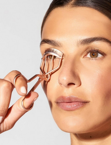 Mujer usando rizador de pestanas clasico Tweezerman color oro rosado