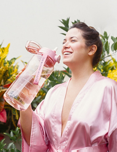 Mujer con botella rosada de agua de 2 litros con mensajes motivacionales de tritan copolyester