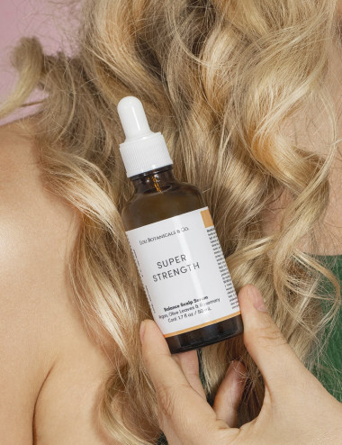 Mujer usando serum que nutre, equilibra y protege el cuero cabelludo. Hecho con argán, olivo y romero